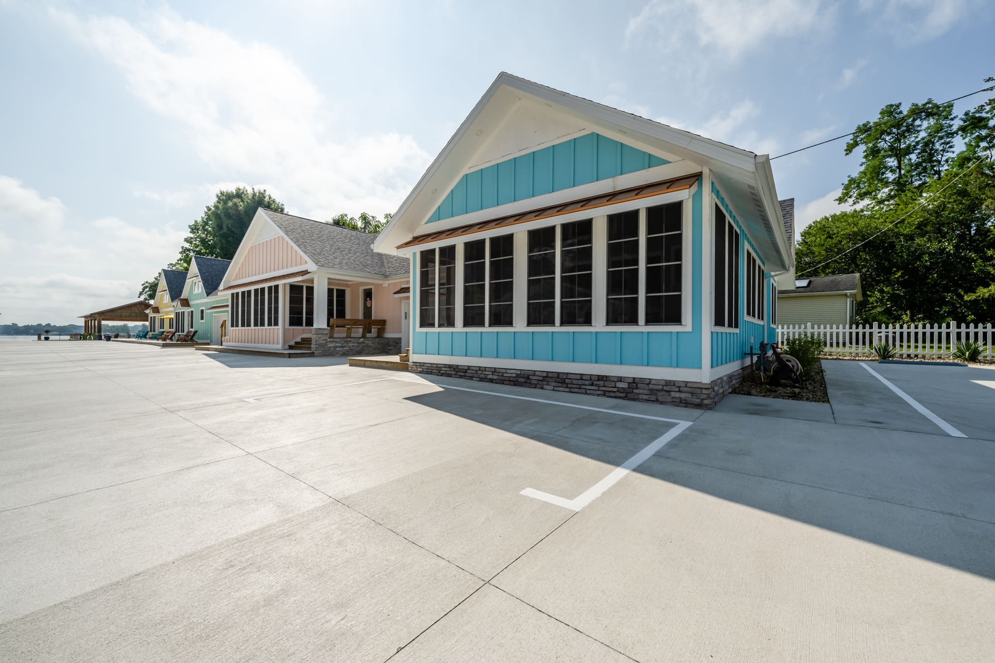 Colorful cottages with pastel siding, wide driveways, and a sunny backdrop